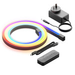 A coiled LED strip light displaying a rainbow of colors is laid out next to a power adapter, a remote control, a power cable, and additional connectors. The image showcases all the included components of the LED lighting kit on a white background.