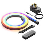 An uncoiled, multi-colored LED light strip placed on a surface, accompanied by a power adapter, a remote control, and two cables. The LED strip displays vibrant hues of blue, pink, yellow, and green.