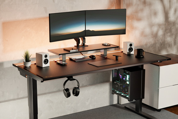 Modern home office setup featuring a large black desk with dual monitors on a raised stand, a mechanical keyboard, a mouse, white speakers, a potted plant, headphones hanging underneath, and a black mug. A gaming PC with colorful internal lighting sits under the desk.